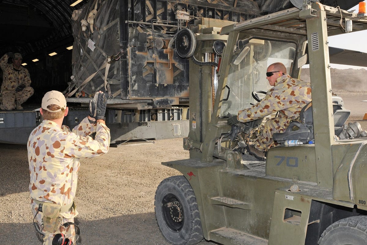 Australian Defence Force personnel loading a pallet into a C-17 aircraft with a forklift